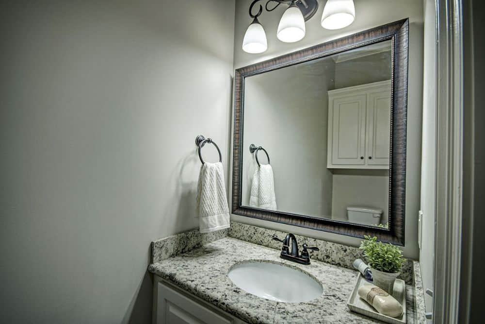 Powder room with a sink vanity paired with a wooden framed mirror.