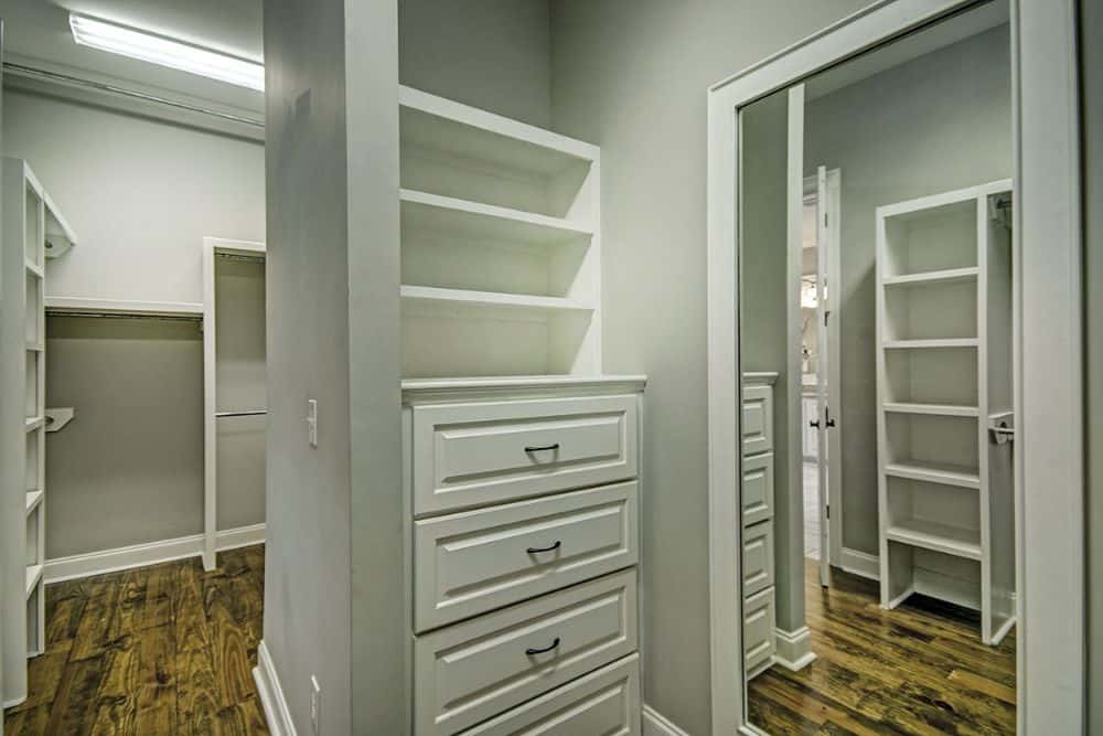 Primary walk-in closet with large mirrors and built-in shelves.
