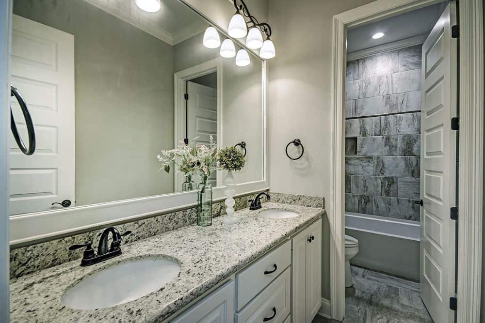 This bathroom is equipped with a double sink vanity, a toilet, and a tub and shower combo.