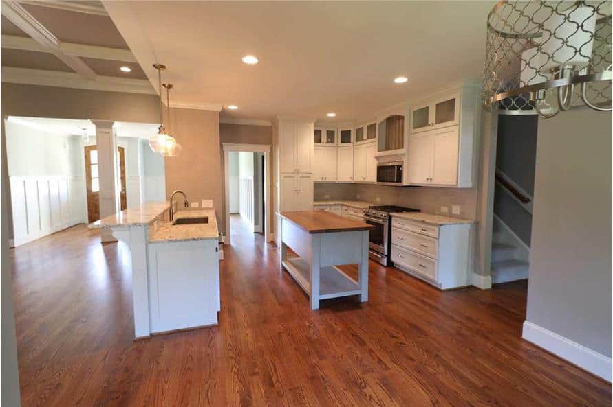 Kitchen with white cabinetry, a center island, and a peninsula topped with a sink and a raised eating bar.