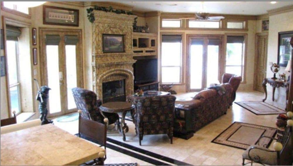 Living room with classic seats, a fireplace, and walls of windows that flood the interior with natural light.