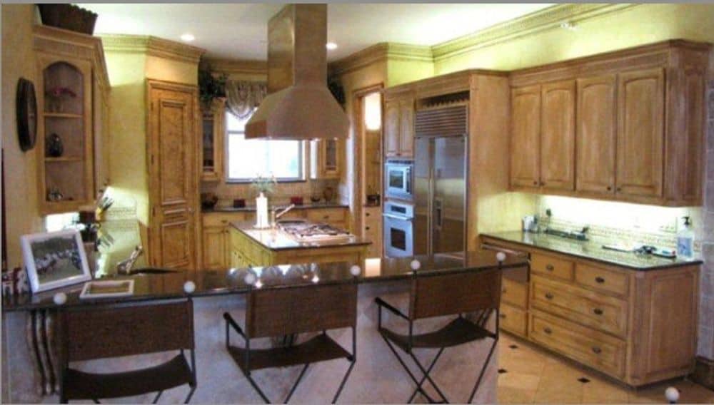 The kitchen features wooden cabinetry, stainless steel appliances, a center island, and an eating bar.