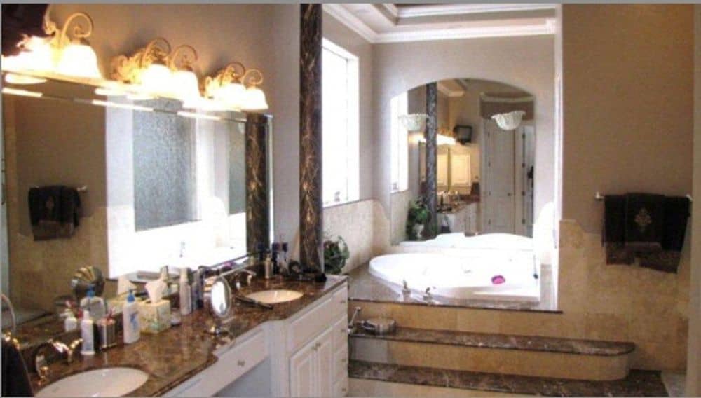 Primary bathroom with dual sink vanity and an alcove tub lined with a decorative column.