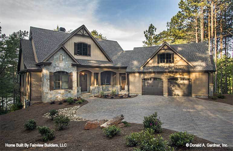 The front view of the house showcases the landscaping of graveled driveway and walkway, miniature gardens of shrubs and rock decorations that pair well with the stone mosaic exterior walls.