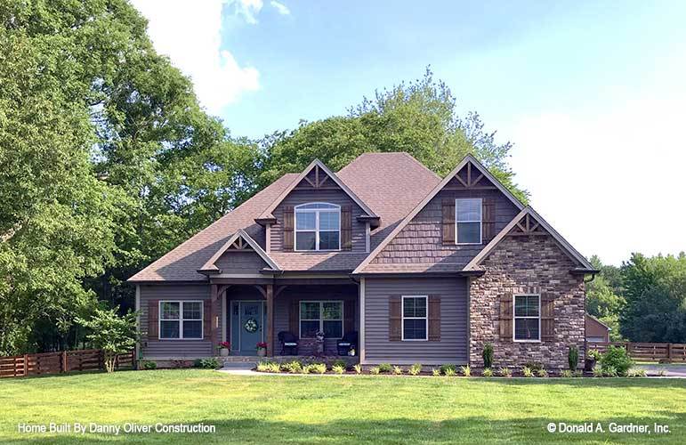 Front exterior view showing the covered entry porch and multiple gables adorned with rustic trims.