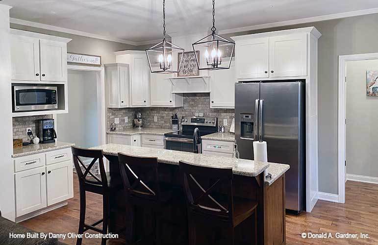 The kitchen is equipped with stainless steel appliances, granite countertops, white cabinetry, and a two-tier island.