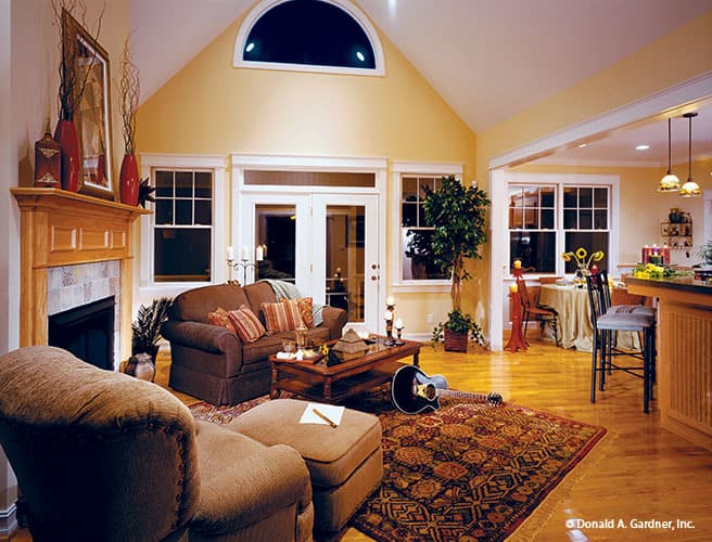 Great room with a cathedral ceiling, an arched transom, brown seats, and a cozy fireplace.