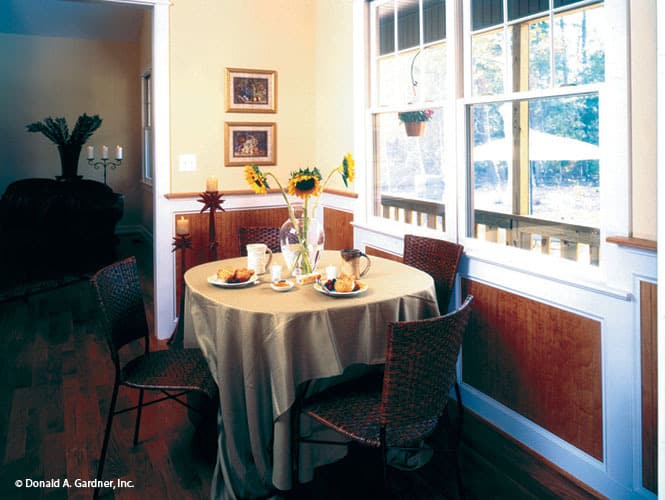 The breakfast nook offers a round dining set for four placed against the white framed window.
