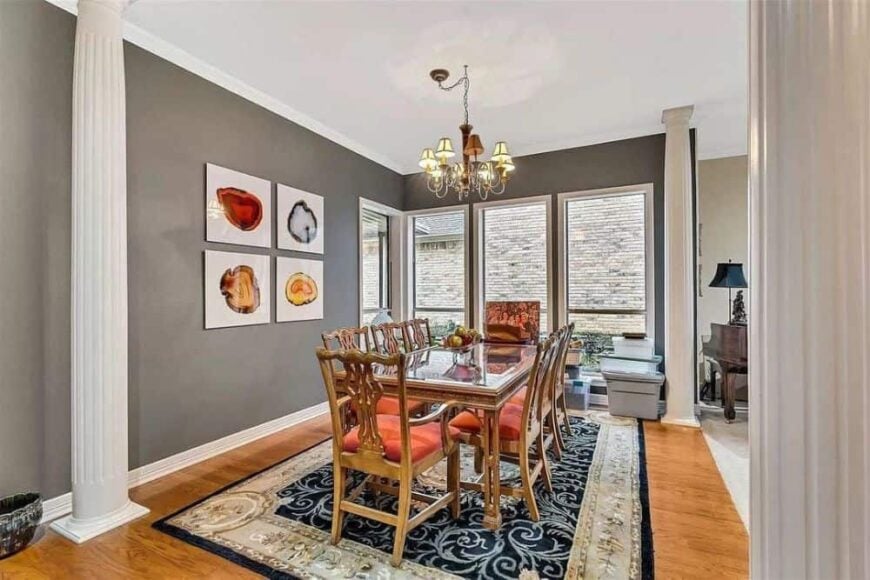 The dining room offers cushioned chairs and a glass top dining table sitting on a bordered area rug.