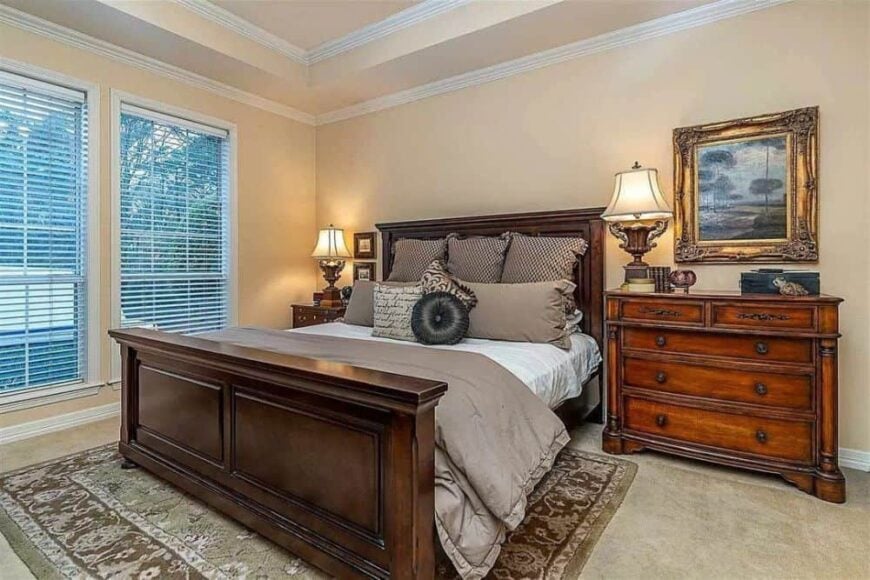 This bedroom has a tray ceiling, wooden furnishings, and a patterned area rug.