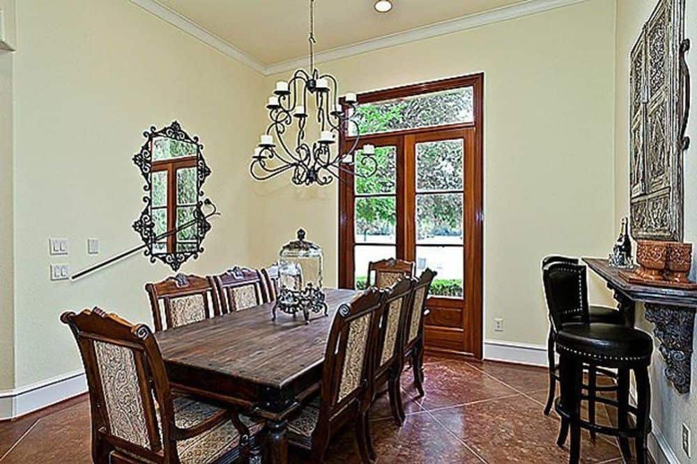 Formal dining room with a decorative mirror and an 8-seater dining set well-lit by an ornate chandelier.