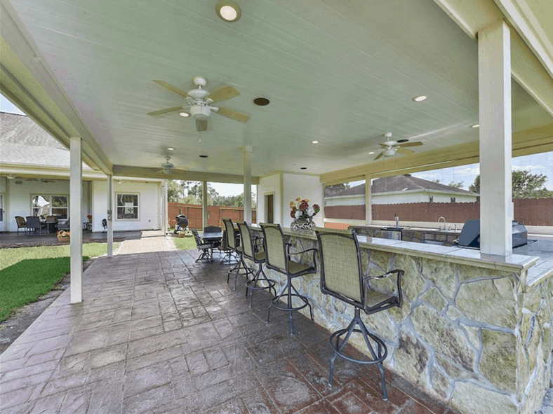 The outdoor kitchen is paired with wrought iron counter chairs.