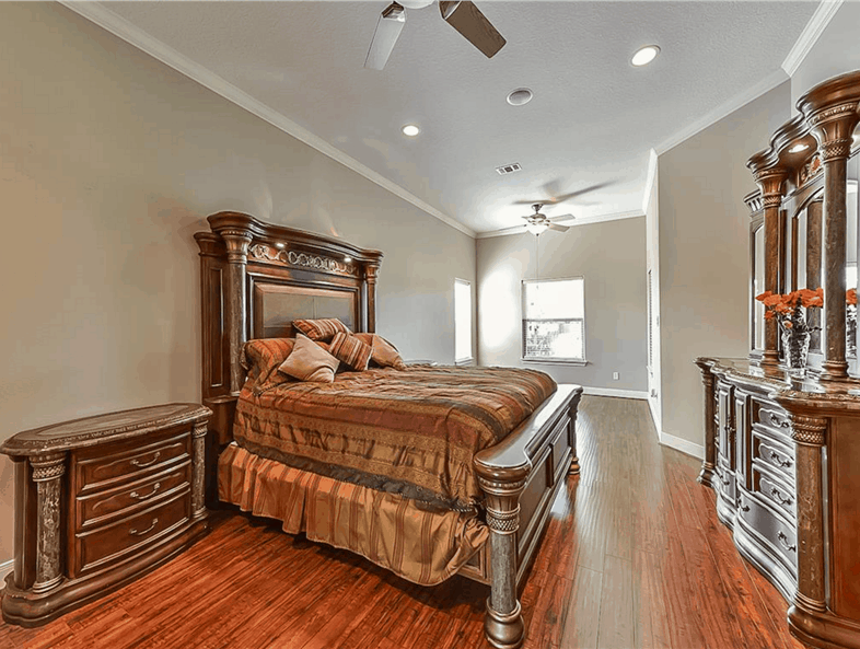 The primary bedroom features dark wood furnishings that blend in with the hardwood flooring.