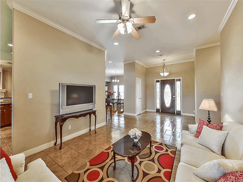 Living room with a beige sectional, an oval coffee table, and a TV sitting on a wooden console table.