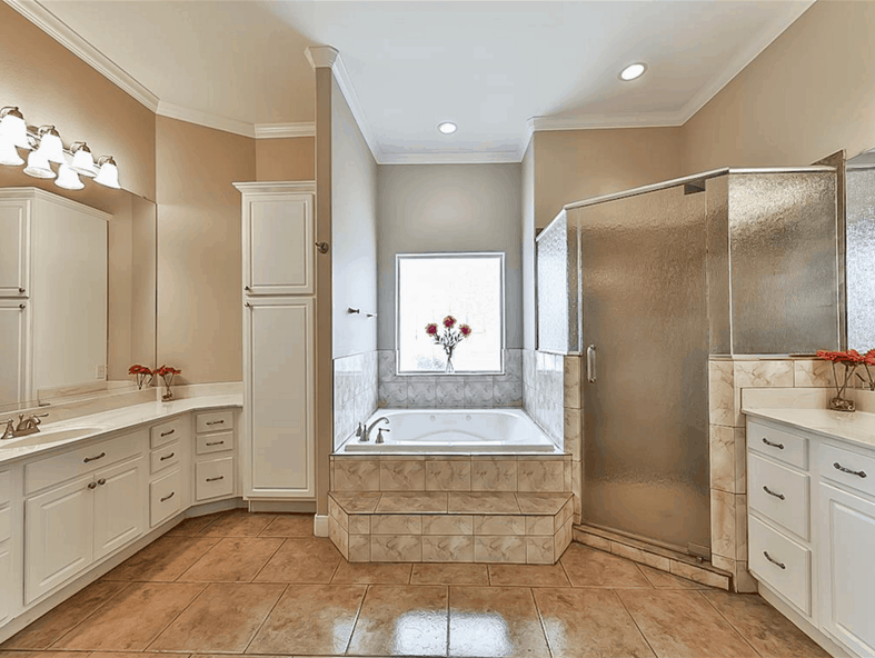 Primary bathroom with his and her sink vanities, a walk-in shower, and a soaking tub placed under the picture window.