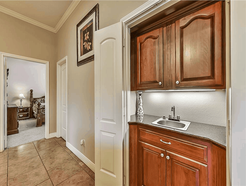 Wet bar with wood cabinets and a granite countertop fitted with a small sink.