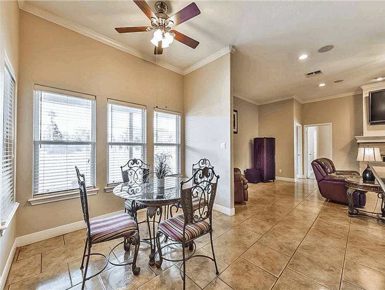 Breakfast nook with a round glass top table paired with ornate iron chairs.