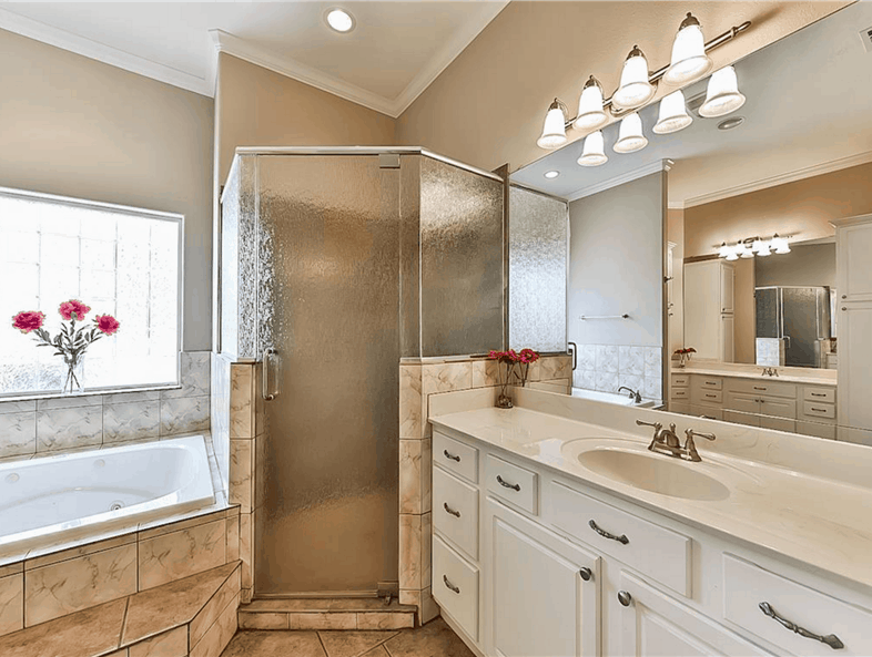 The walk-in shower is encased in frosted glass panels with a hinged door.