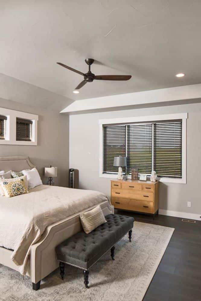 The primary bedroom features a beige upholstered bed complemented with a tufted bench.