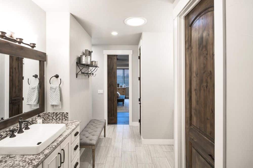 Primary bathroom with a cushioned bench, a metal shelf, and single sink vanity.