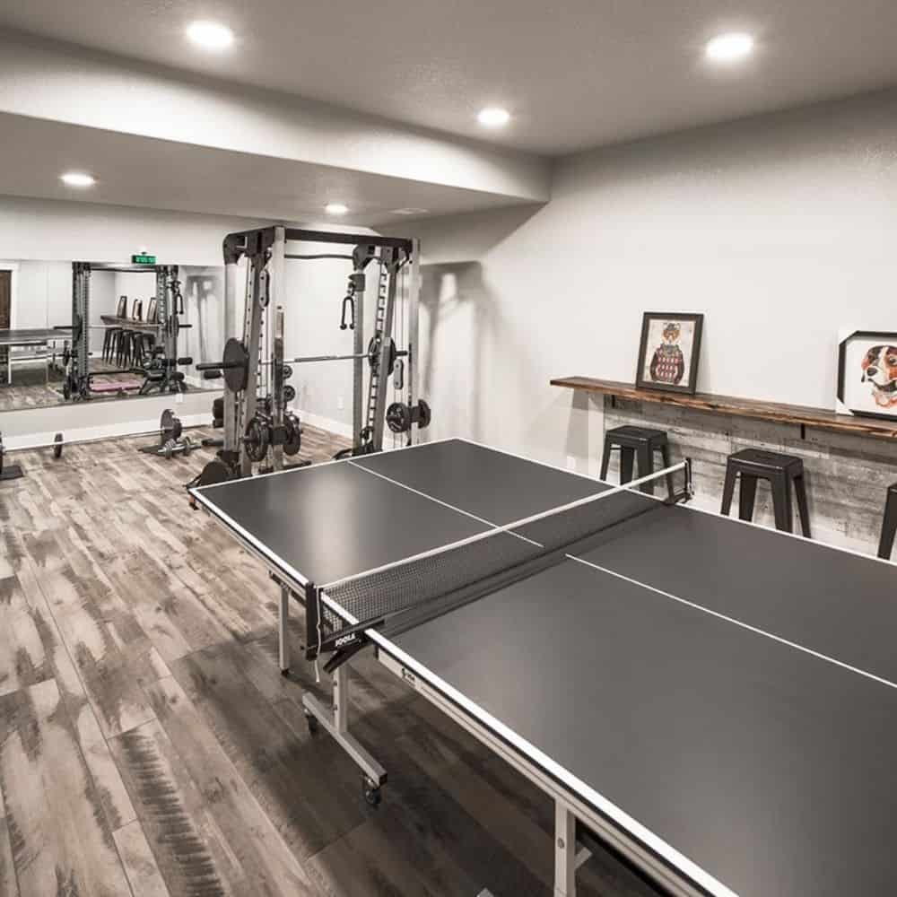 The recreation room is filled with a ping pong table, gym equipment, and a built-in bar.