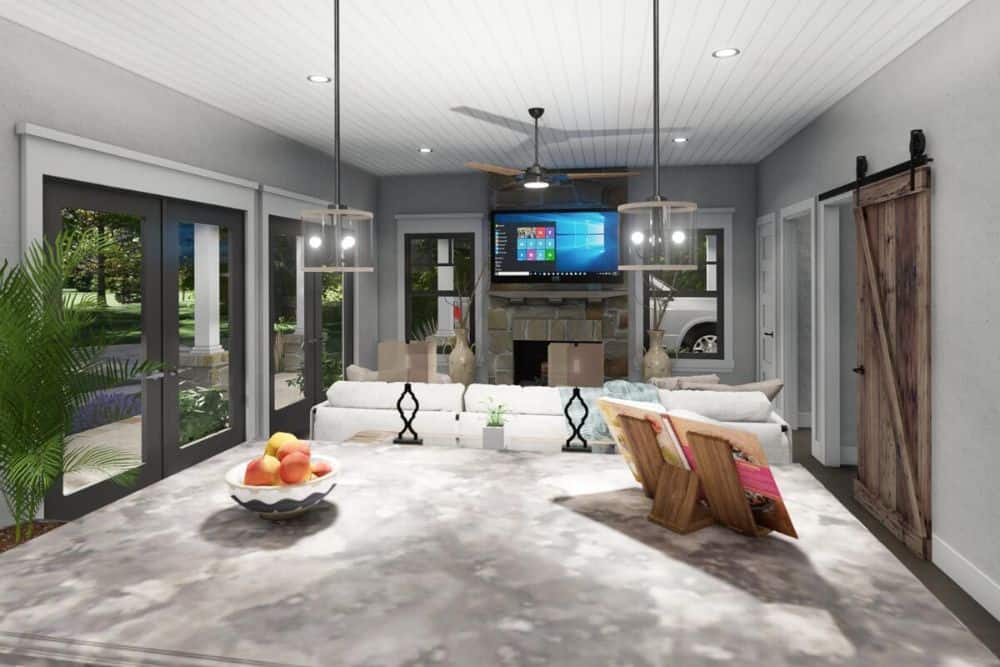 View of the family room from the kitchen showing the stone fireplace and wall-mounted TV.