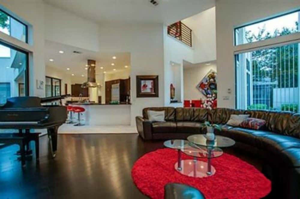 Living room with a baby grand piano and a curved leather sectional paired with a glass modular coffee table.