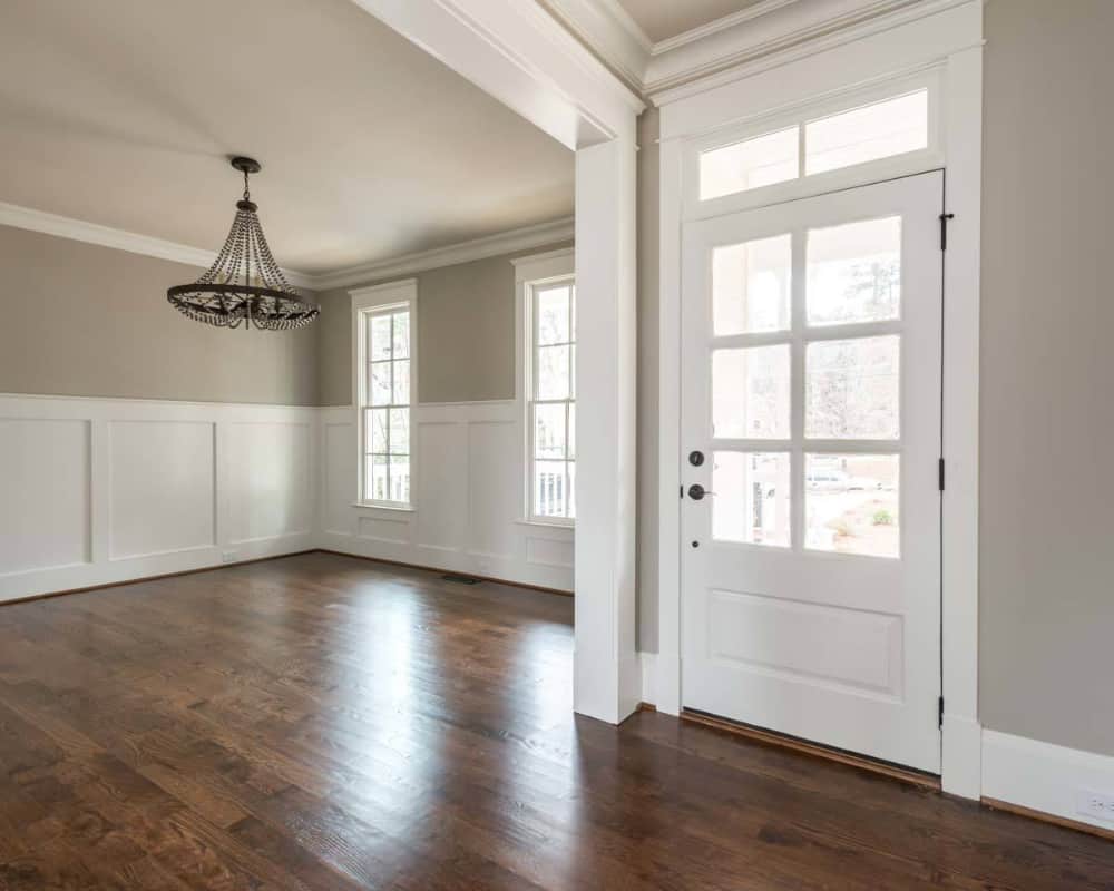 The foyer opens into the formal dining room with wainscoted walls and a wrought iron chandelier.