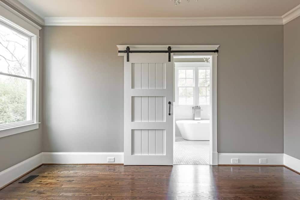A sliding barn door reveals the primary bathroom.