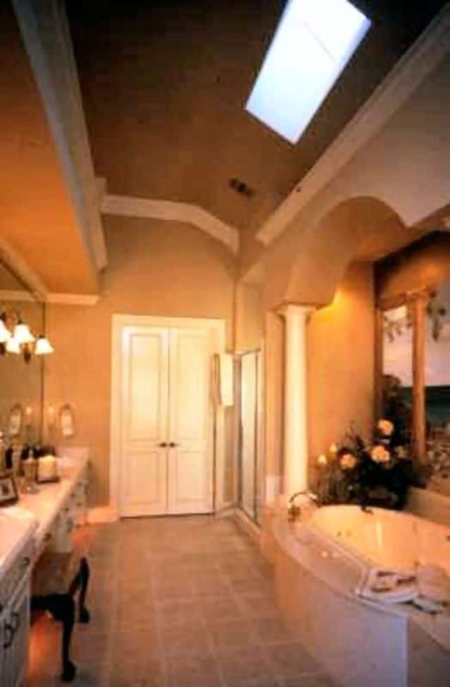 The primary bathroom offers a dual sink vanity and a deep soaking tub framed with a decorative arch.