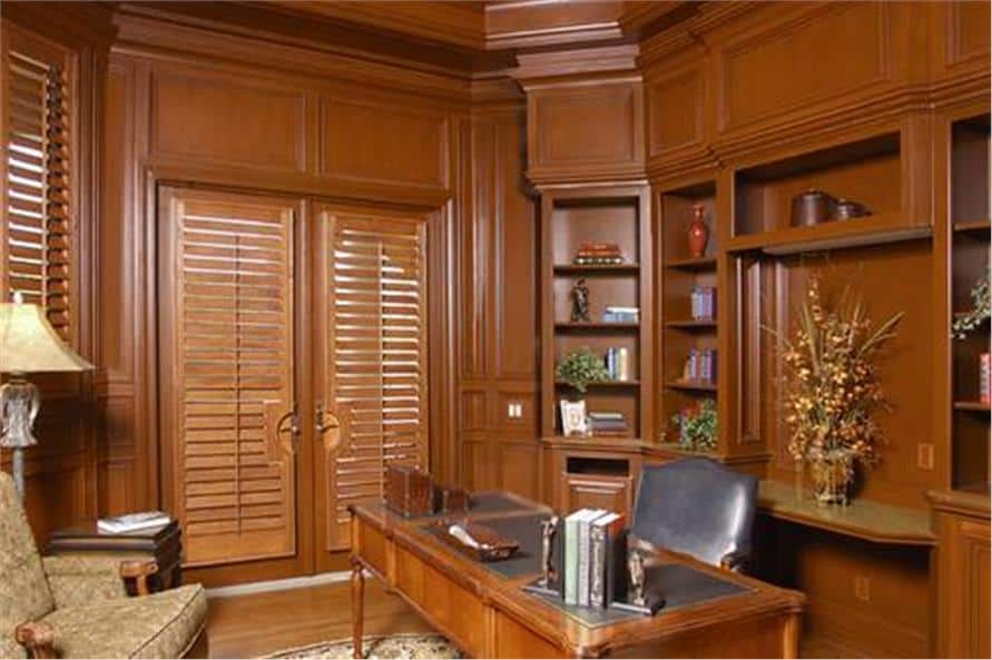The study features a wooden desk with a medium tone that matches with the built-in shelves and paneled walls.