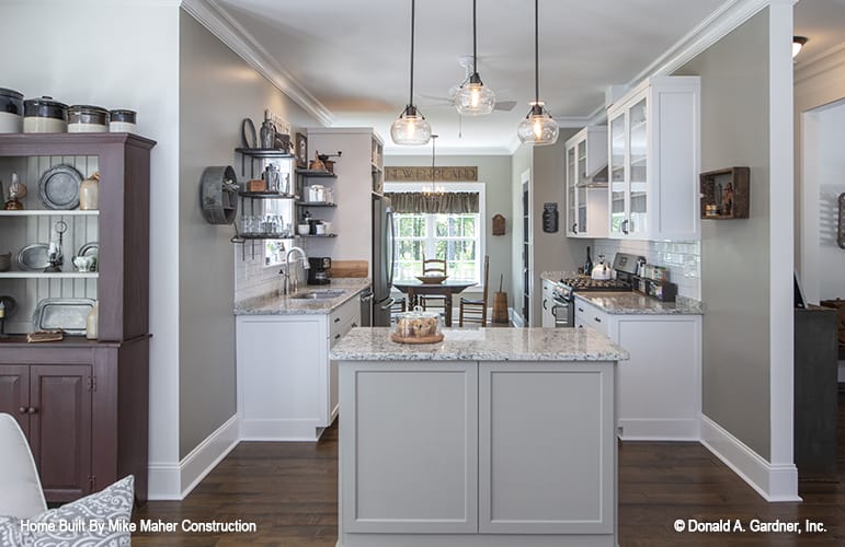 The kitchen offers white cabinets, granite countertops, and a breakfast bar well-lit by glass dome pendants.