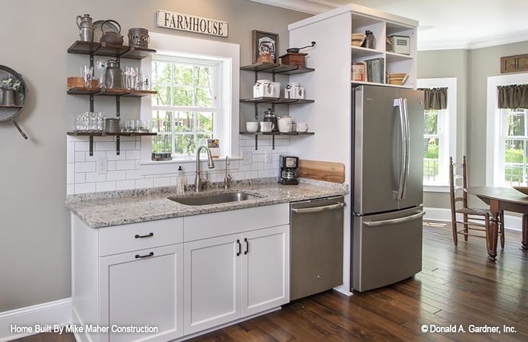 The kitchen includes stainless steel appliances and an undermount sink fixed under the framed window.