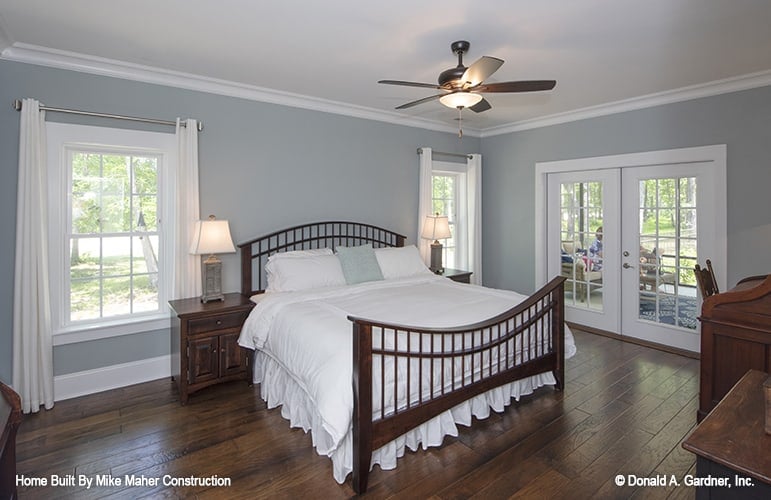 Primary bedroom with gray walls and dark wood furnishings that blend in with the hardwood flooring.