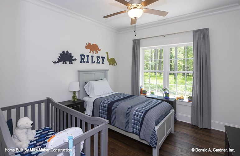 Another bedroom with hardwood flooring, a gray bed, and a matching crib.
