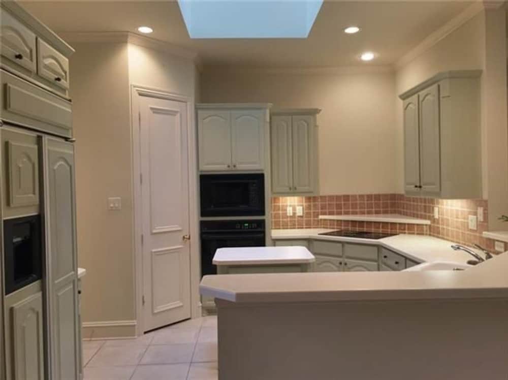 Kitchen with black appliances, white cabinetry, a small center island, and a peninsula with a raised eating bar.