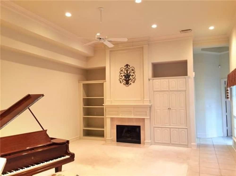 Family room with a baby grand piano and a fireplace flanked by white built-ins.