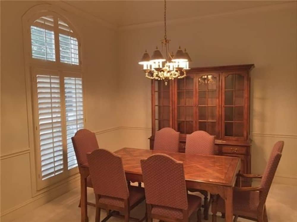 The formal dining room offers a louvered window, a china cabinet, and a 6-seater dining set illuminated by a classic chandelier.