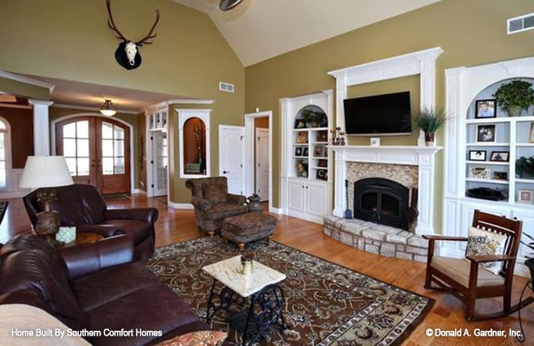 Great room with comfy seats, white built-ins, and a stone fireplace topped with a TV.