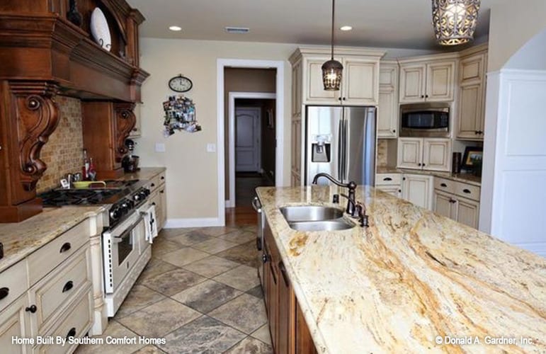 The kitchen offers white cabinetry, stainless steel appliances, and a center island fitted with a double bowl sink.