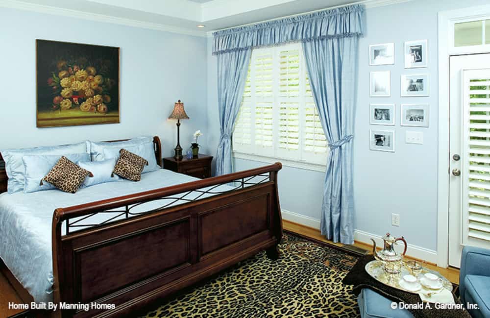 The primary bedroom features a cozy wooden bed, animal-print area rug, and a louvered window leading to the screened porch.