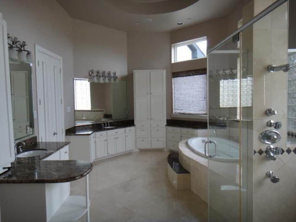 The primary bathroom is equipped with his and her vanities, a deep soaking tub, and a walk-in shower.