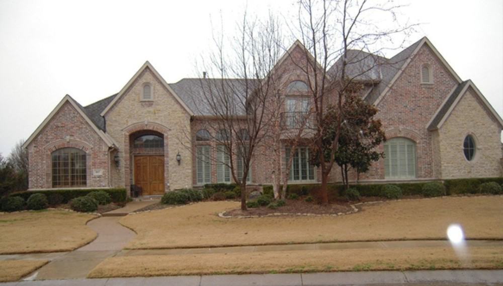 Front exterior view showing the stone and brick siding, arch windows, and multiple gables with varying peaks.