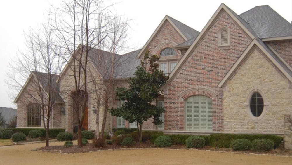 Tall plants and manicured shrubs complement the two-story traditional home.