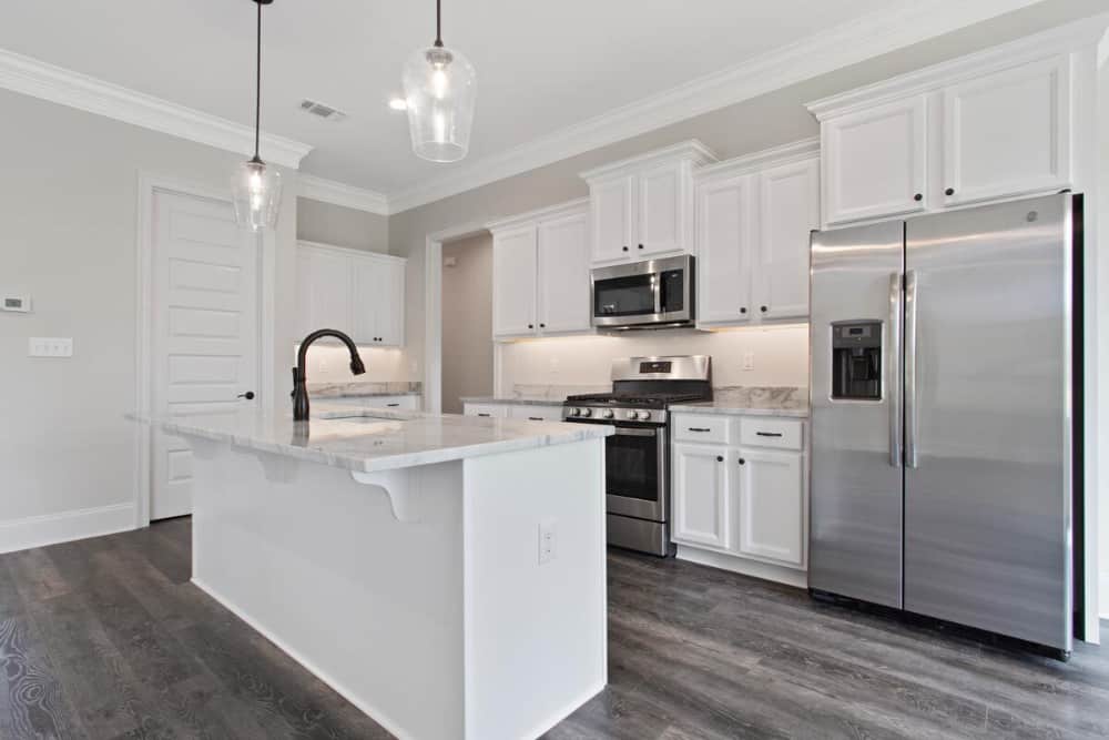 The kitchen offers white cabinetry, stainless steel appliances, and a center island fitted with a sink.