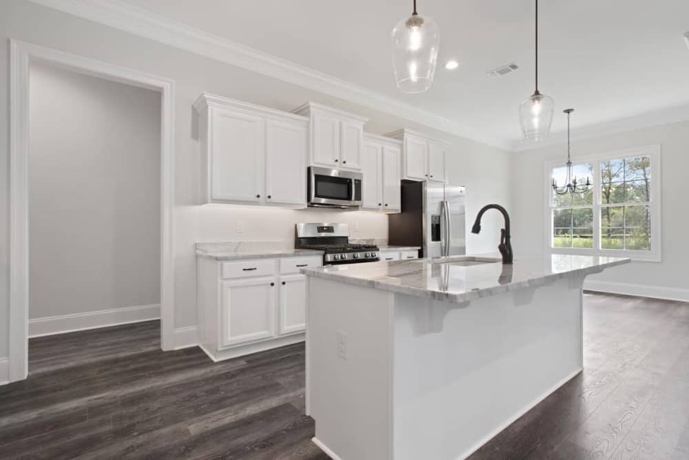 Glass pendants over the island along with natural light from the white framed window brighten the kitchen.
