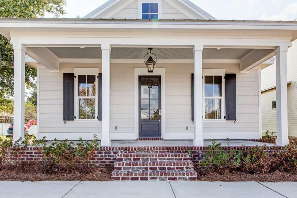 A closer look at the entry porch showing the brick stoop and glazed front door flanked by shuttered windows.