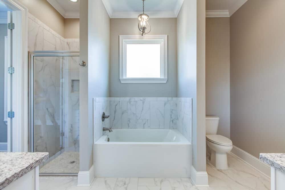 Across the vanities are the toilet, drop-in tub, and walk-in shower.