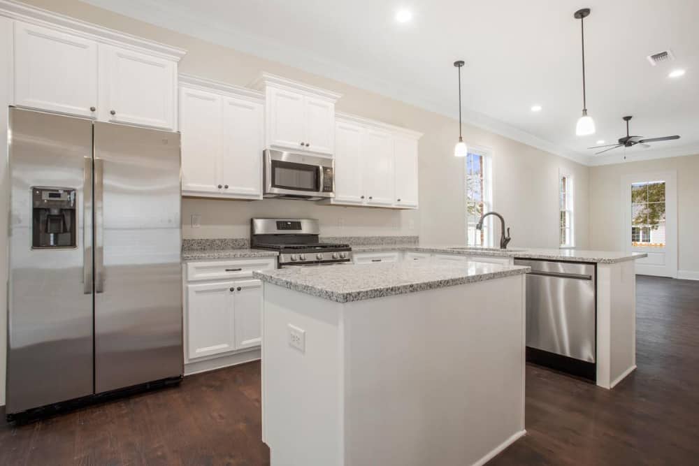 Kitchen with stainless steel appliances, granite countertops, white cabinetry, and a center island.