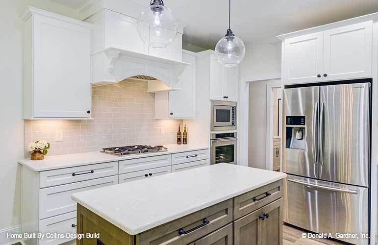 The kitchen includes a center island well-lit by glass dome pendants.